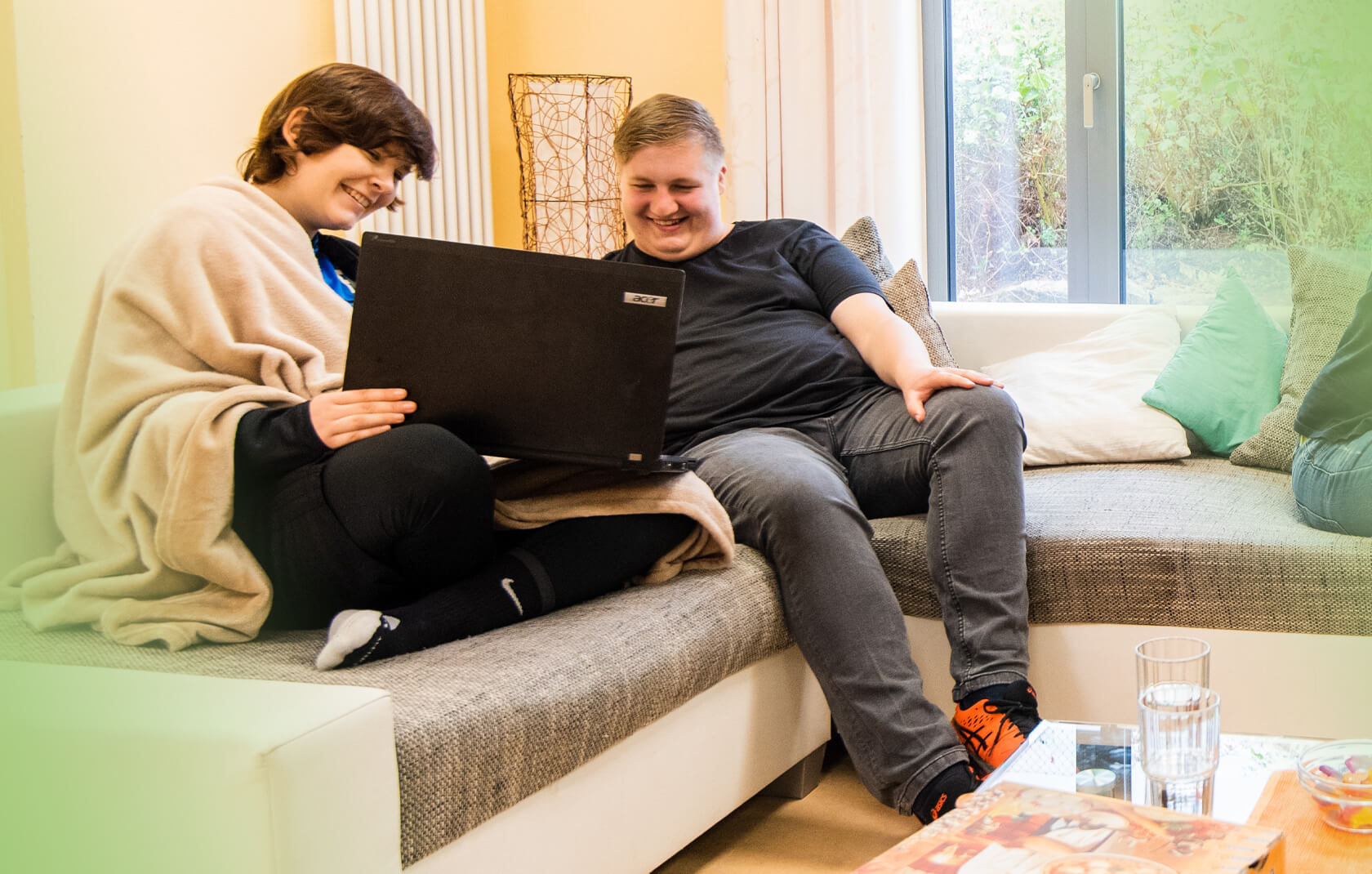 Junge Frau und junger Mann am Laptop auf der Couch der Jugendhilfe des bbw Südhessen