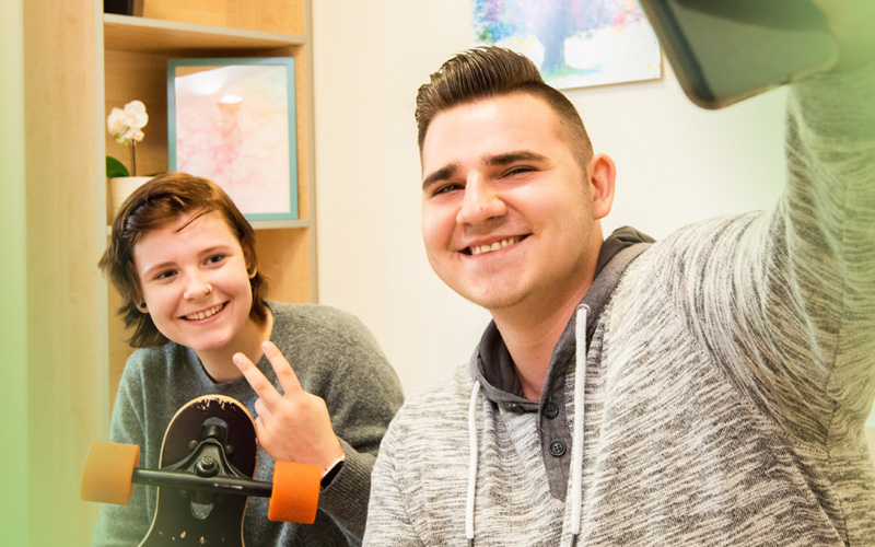 2 Jugendliche machen ein Selfie mit dem Handy in der Jugendhilfe des bbw Südhessen